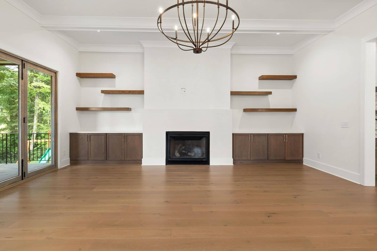 Large open room with a new oak plank floor, fireplace wall with built-in shelves, and a chandelier