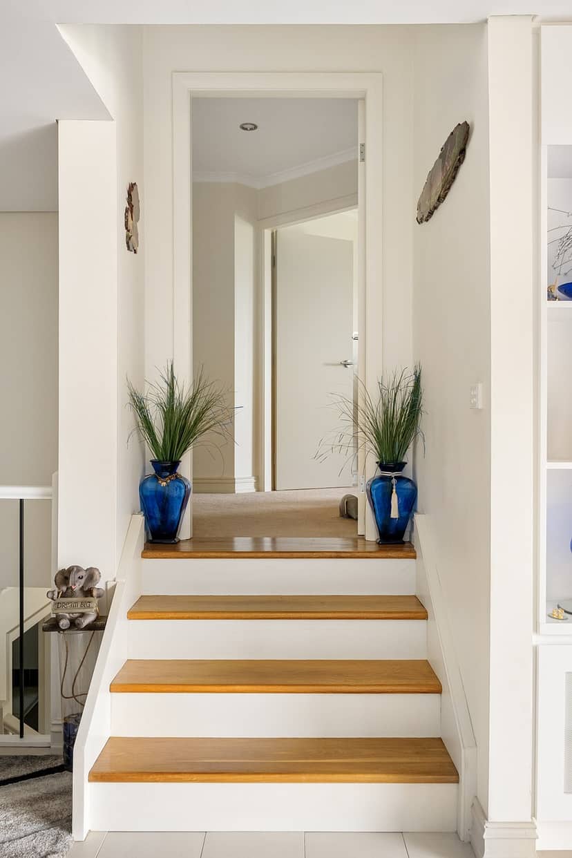 Oak hardwood stair treads with white risers in a narrow stairwell