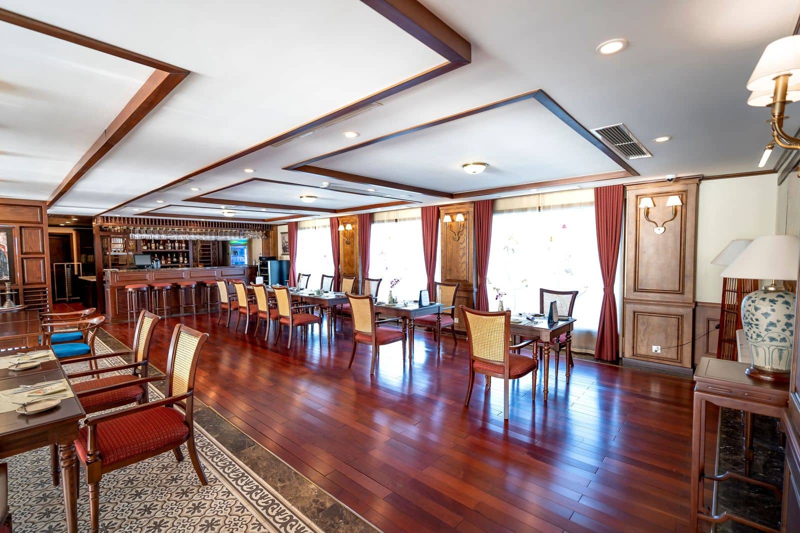 Restaurant dining room with a red-toned hardwood floor, tables, and chairs