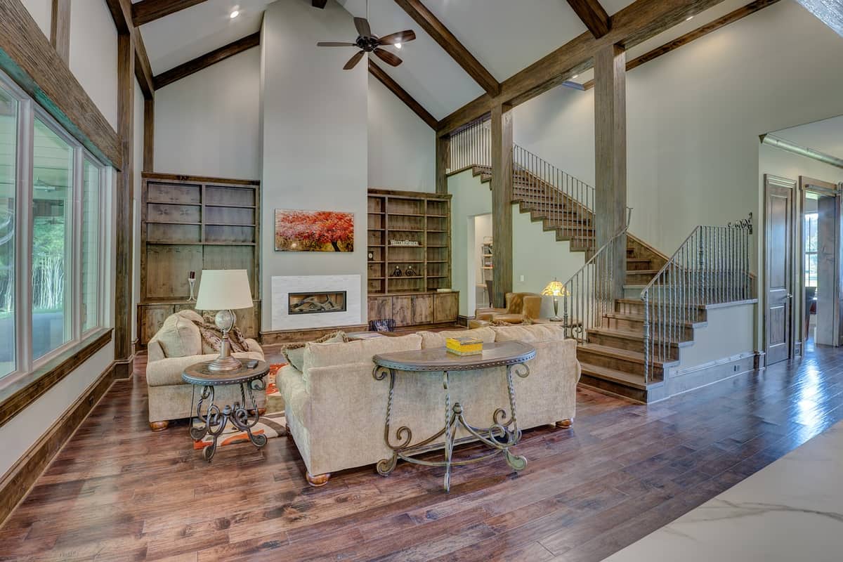 Dark solid hardwood floor in a timber-frame great room with a wood staircase