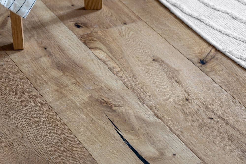 Wide rustic oak planks with knots and natural checks beside a rug